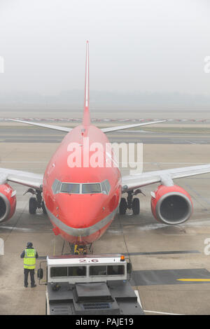 Mann Gelb hohe-viz Waffenrock mit Sterling Airways Boeing737-700 geschoben werden - zurück von einem Schlepper Stockfoto