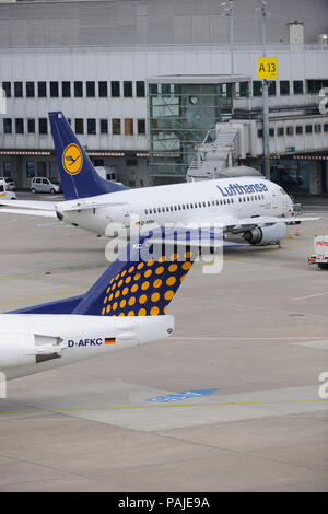 Heckflosse von Contact Air interregionale Fokker 100 Rollen und Lufthansa Boeing 737 am Terminal hinter geparkt Stockfoto