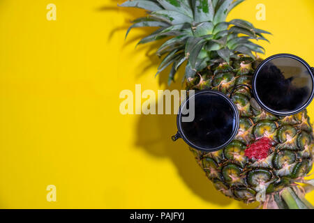 Nahaufnahme reife rote Lippe Ananas mit Sonnenbrille auf gelben Hintergrund, Kopie Raum Stockfoto