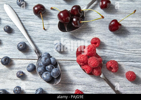 Früchte Muster von frischem Sommer, Blaubeeren, Kirschen, Himbeeren auf grauem Hintergrund. Ansicht von oben. Stockfoto