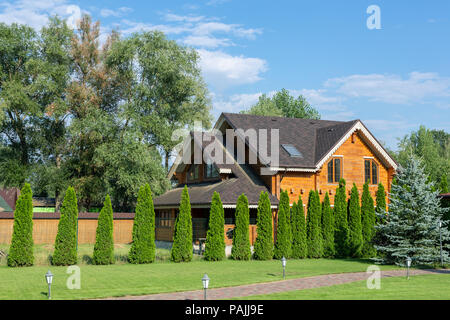 Schönen Luxus big Holzhaus. Holz Landhaus Villa mit grünem Rasen, Garten und blauer Himmel im Hintergrund. Stockfoto
