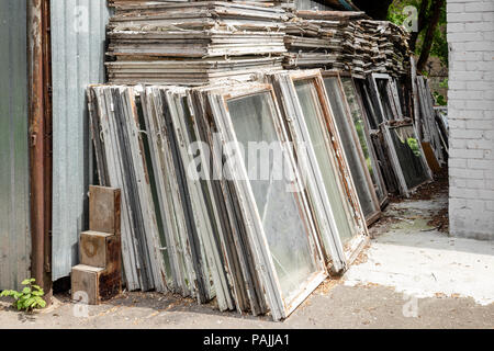 Haufen von alten hölzernen Fensterrahmen mit Glas im Außenbereich. Gebrochene Materialien nach Fenster energiesparende Technologie aufrüsten. Stockfoto