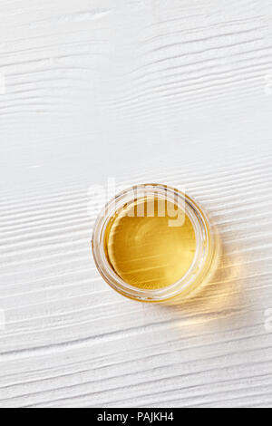 Organic Natural Honig in einem Glas auf einem weißen Holz- Hintergrund. Flach. Stockfoto