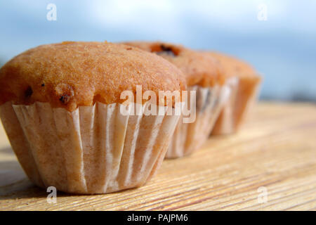 Mehrere Muffins auf einem Holztisch auf dem Himmel Hintergrund Stockfoto