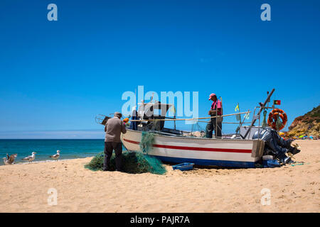 Kleinen Fischer ihre Netze Reinigung, in Salema an der Algarve, Portugal. Stockfoto