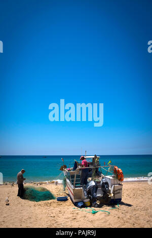 Kleinen Fischer ihre Netze Reinigung, in Salema an der Algarve, Portugal. Stockfoto