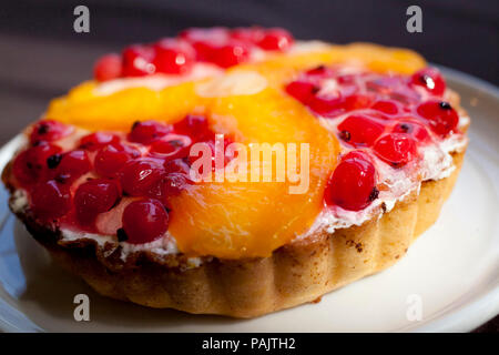 Bunte und leckere Kuchen, Tarte mit roten Johannisbeeren und Mandarin serviert auf weiße Platte Stockfoto