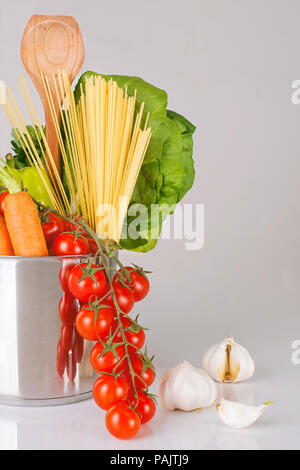 Vielzahl von frischem Gemüse, Schaufel und Spaghetti in einem Topf auf einem grauen Hintergrund, Vertikal, grauer Hintergrund Stockfoto