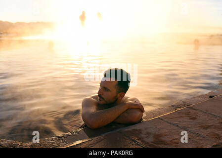 Mann baden in den heißen Quellen, mit Sunrise beleuchtet Dampf im Hintergrund. Termas de Polques, Sud Lípez, Bolivien. Stockfoto