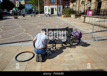 Blackbun Stadtzentrum in Lancashire, England, das Rathaus Radfahrer zur Festsetzung eines platten Reifens auf seinem Fahrrad Stockfoto