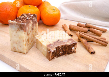 Traditionelle hausgemachte Seife mit Orange und Zimt Aroma auf einem Holz Schneidebrett mit einem Handtuch auf dem Hintergrund Stockfoto