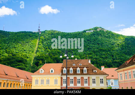 Brasov schreiben auf der Tampa Hügel mit der frischen, grünen Wald und verlegen Sie das Kabel im Hintergrund und historische Gebäude im Vordergrund Stockfoto