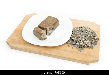Halva oder halvah Traditionelle orietnal und Osteuropa Dessert aus Sonnenblumenkernen und Kakao auf einer weißen Platte auf einem Holz cutiing Board auf einem whit gemacht Stockfoto
