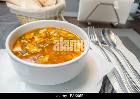 Gemüsesuppe in einem Restaurant in einem weißen Boul mit Brot auf dem Hintergrund Stockfoto