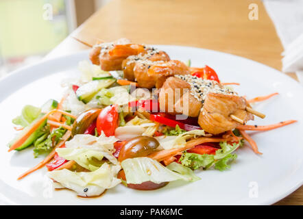 Wald Salat mit hähnchenspieße Souvlaki auf einer weißen Platte an einem sonnigen Tag Stockfoto