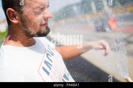 Hannover, Deutschland. 23. Juli 2018. Bauarbeiter Mirko Abkühlung von der heißen Temperaturen mit Wasser aus einem Schlauch bei Reparaturarbeiten auf einer Brücke. Ist es doppelt warm für Mirko in diesen heißen Tagen: die Sonne brennt von oben und das Feuer brennt der Gasbrenner von unten. Credit: Julian Stratenschulte/dpa/Alamy leben Nachrichten Stockfoto