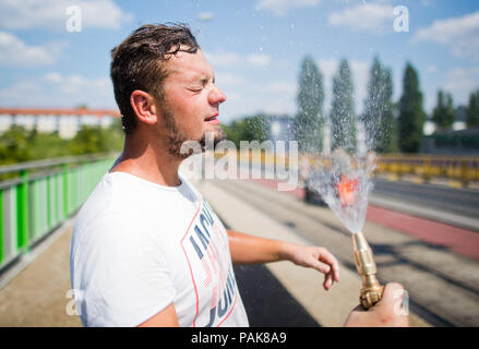 Hannover, Deutschland. 23. Juli 2018. Bauarbeiter Mirko Abkühlung von der heißen Temperaturen mit Wasser aus einem Schlauch bei Reparaturarbeiten auf einer Brücke. Ist es doppelt warm für Mirko in diesen heißen Tagen: die Sonne brennt von oben und das Feuer brennt der Gasbrenner von unten. Credit: Julian Stratenschulte/dpa/Alamy leben Nachrichten Stockfoto