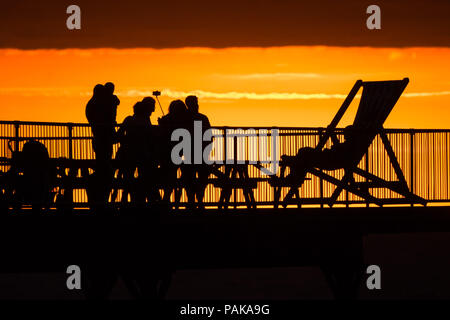 Aberystwyth Wales UK, Montag, 23. Juli 2018 UK Wetter: Menschen, die von den herrlichen Sonnenuntergang über Aberystwyth Pier Silhouette am Ende der heißesten Tag des Sommers so weit, mit Temperaturen Hoechststand von 33,3°C im Santon Downham, Suffolk. Großbritannien große Hitzewelle fort, ohne Atempause von der sehr trockenen Wetter, und das Met Office hat ein 'Wärme Health Watch Alert für viel der Osten und Südosten Englands Photo Credit: Keith Morris/Alamy Live Neuigkeiten Stockfoto