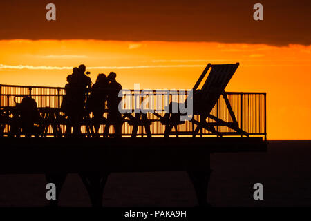 Aberystwyth Wales UK, Montag, 23. Juli 2018 UK Wetter: Menschen, die von den herrlichen Sonnenuntergang über Aberystwyth Pier Silhouette am Ende der heißesten Tag des Sommers so weit, mit Temperaturen Hoechststand von 33,3°C im Santon Downham, Suffolk. Großbritannien große Hitzewelle fort, ohne Atempause von der sehr trockenen Wetter, und das Met Office hat ein 'Wärme Health Watch Alert für viel der Osten und Südosten Englands Photo Credit: Keith Morris/Alamy Live Neuigkeiten Stockfoto