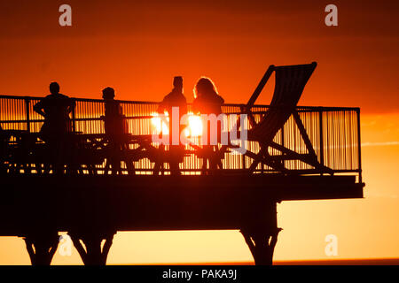 Aberystwyth Wales UK, Montag, 23. Juli 2018 UK Wetter: Menschen, die von den herrlichen Sonnenuntergang über Aberystwyth Pier Silhouette am Ende der heißesten Tag des Sommers so weit, mit Temperaturen Hoechststand von 33,3°C im Santon Downham, Suffolk. Großbritannien große Hitzewelle fort, ohne Atempause von der sehr trockenen Wetter, und das Met Office hat ein 'Wärme Health Watch Alert für viel der Osten und Südosten Englands Photo Credit: Keith Morris/Alamy Live Neuigkeiten Stockfoto