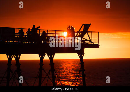 Aberystwyth Wales UK, Montag, 23. Juli 2018 UK Wetter: Menschen, die von den herrlichen Sonnenuntergang über Aberystwyth Pier Silhouette am Ende der heißesten Tag des Sommers so weit, mit Temperaturen Hoechststand von 33,3°C im Santon Downham, Suffolk. Großbritannien große Hitzewelle fort, ohne Atempause von der sehr trockenen Wetter, und das Met Office hat ein 'Wärme Health Watch Alert für viel der Osten und Südosten Englands Photo Credit: Keith Morris/Alamy Live Neuigkeiten Stockfoto