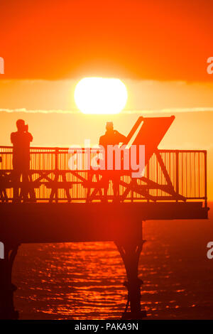 Aberystwyth Wales UK, Montag, 23. Juli 2018 UK Wetter: Menschen, die von den herrlichen Sonnenuntergang über Aberystwyth Pier Silhouette am Ende der heißesten Tag des Sommers so weit, mit Temperaturen Hoechststand von 33,3°C im Santon Downham, Suffolk. Großbritannien große Hitzewelle fort, ohne Atempause von der sehr trockenen Wetter, und das Met Office hat ein 'Wärme Health Watch Alert für viel der Osten und Südosten Englands Photo Credit: Keith Morris/Alamy Live Neuigkeiten Stockfoto