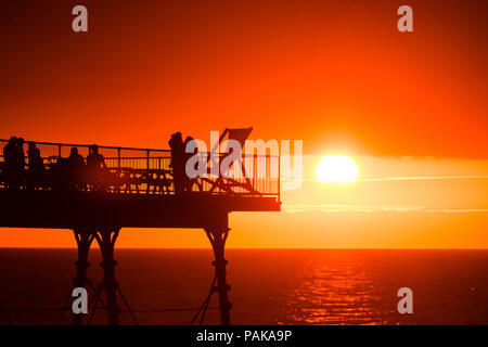 Aberystwyth Wales UK, Montag, 23. Juli 2018 UK Wetter: Menschen, die von den herrlichen Sonnenuntergang über Aberystwyth Pier Silhouette am Ende der heißesten Tag des Sommers so weit, mit Temperaturen Hoechststand von 33,3°C im Santon Downham, Suffolk. Großbritannien große Hitzewelle fort, ohne Atempause von der sehr trockenen Wetter, und das Met Office hat ein 'Wärme Health Watch Alert für viel der Osten und Südosten Englands Photo Credit: Keith Morris/Alamy Live Neuigkeiten Stockfoto