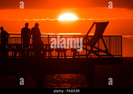 Aberystwyth Wales UK, Montag, 23. Juli 2018 UK Wetter: Menschen, die von den herrlichen Sonnenuntergang über Aberystwyth Pier Silhouette am Ende der heißesten Tag des Sommers so weit, mit Temperaturen Hoechststand von 33,3°C im Santon Downham, Suffolk. Großbritannien große Hitzewelle fort, ohne Atempause von der sehr trockenen Wetter, und das Met Office hat ein 'Wärme Health Watch Alert für viel der Osten und Südosten Englands Photo Credit: Keith Morris/Alamy Live Neuigkeiten Stockfoto