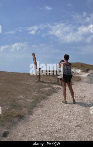 Beachy Head, East Sussex, UK. 24. Juli, 2018. Trotzt eine schriftliche Verwarnung, ein junges Weibchen touristische Risiken Tod für ein Foto bei Beachy Head, East Sussex. Die Kreidefelsen sind notorius für Selbstmorde und Rock fällt vom erodierenden Klippen. Credit: Dario Earl/Alamy leben Nachrichten Stockfoto