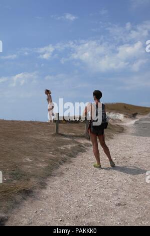 Beachy Head, East Sussex, UK. 24. Juli, 2018. Ein Tourist nimmt eine Gefahr für ein Foto, trotz schriftlicher Mahnung nicht in der Nähe der Steilküste. Beachy Head in East Sussex ist berüchtigt für Selbstmorde und und Rock fällt vom Erodieren chalk Gesicht. Credit: Dario Earl/Alamy leben Nachrichten Stockfoto