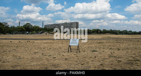 London, Großbritannien. 24. Juli, 2018. London erhält eine Atempause mit einigen Cloud, aber immer noch kein Regen im Süden Londons, wo das Gras in Burgess Park mehr wie Sand mit dem Wendover Block des Aylesbury Immobilien sieht im Hintergrund mit dem Shard ausgetrocknet. David Rowe/Alamy Leben Nachrichten. Stockfoto