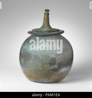 Glas cinerary Urne mit Deckel. Kultur: Roman. Abmessungen: H: 12 cm. (30,8 cm). Datum: 1.-Anfang 2.Jh. N.CHR.. Jar (A): Transluzent blau grün. Breite, röhrenförmige Rim, Ausgeklappt, unten, und bildet ungleichmäßige, wellige Oberfläche; kugelförmigen Körper; konkave Unterseite. Abgeschlossen, aber ein Riss in der Felge und der oberen Seite; nadelstich und ein paar größere Blasen; einige Lochfraß, Mattieren, und irisierenden Bewitterung im Außenbereich, brillante Schillern und cremig Überstehen auf Interieur. Ein Band der unregelmäßige horizontale Linien auf den oberen Teil des Körpers gerade unterhalb der Felge zerkratzt, vermutlich aus verwenden. Deckel (B): Transluc Stockfoto