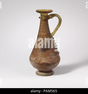 Glaskanne. Kultur: Roman. Abmessungen: H.: 6 3/16 in. (15,7 cm). Datum: 4.Jahrhundert N.CHR.. Durchscheinende Licht gelb grün; Griff und in der gleichen Farbe Trail. Auch rim mit dicken, runden Lippe; kurz, abfackeln Mund; hohe, langgestreckte piriform Körper; outsplayed, röhrenförmige Fußring, durch Falten; konkaver Boden mit zentralen Kick und pontil Narbe; breiter Griff der Stange zum oberen Körper befestigt, mit Schwanz nach unten verlängern, bis in einer geschwungenen Kurve gezeichnet und Angewandte am Oberteil des Körpers zu Trail, und verstummte entlang zurück. Eine dicke Spur wunde Eineinhalb Mal horizontal auf der Oberseite des Körpers; die Tai Stockfoto