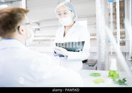 Porträt von zwei moderne junge Wissenschaftler tragen Laborkittel sprechen, während im medizinischen Labor Stockfoto