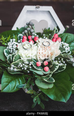 Zwei weiße Gold Trauringe in Schatulle close-up mit frischen Blumen für die Hochzeit Stockfoto