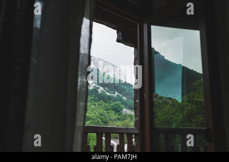Bergblick durch offene Fenster auf dem Balkon, Felsen in trüben und nebligen Wetter Stockfoto