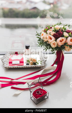 Hochzeit-Blumenstrauß mit Rosen, Pfingstrosen und Seide Bänder, Ringe, Parfüm, Einladungskarten, Anstecker auf silbernem Tablett Stockfoto