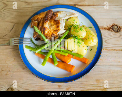 Ein viertel Brathähnchen mit neuen Kartoffeln, Karotten, grüne Bohnen und gehackten Schnittlauch auf einer hölzernen Tischplatte Mittagessen Stockfoto