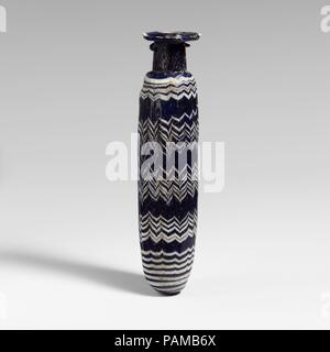 Glas alabastron (Parfüm Flasche). Kultur: Griechisch, östlichen Mittelmeer. Abmessungen: H.: 4 13/16-in. (12,2 cm). Datum: Ende 4./Anfang 3.Jh. v. Chr.. Transluzente Kobaltblau, mit Griffen in der gleichen Farbe; Wanderwege in opak weiß. Horizontale rim-disk, mit dicken abgerundete Kante; hohe zylindrische Hals, verjüngt sich nach oben abgerundete Schulter; Gerade-seitig zylindrische Körper, in geschwungenen unten mit leicht Spitze zu konvex. Eine Spur an der Kante der RIM-disk verbunden; auf Körper, ein Single Trail Wunde in eine Spirale, bilden fünf horizontale Bänder, Oben und Unten wie fast horizontale Linien, sondern auf die meisten o Stockfoto