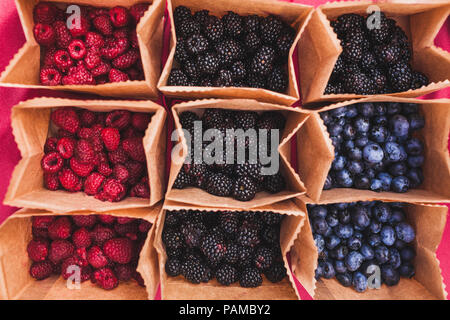 Satz von verschiedenen frischen Beeren in kleinen Handwerksbetrieben Papier Boxen auf Hochzeitsfeier Tabelle, rustikaler Stil, Sommer Stimmung Stockfoto