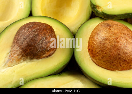 Nahaufnahme von Avocado Schnitt zu Hälfte, braunen Samen sichtbar, mit mehr Avocados im Hintergrund Stockfoto