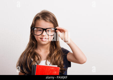 Porträt von einem kleinen Mädchen mit großen Brillen in Studio auf einem weißen Hintergrund. Stockfoto