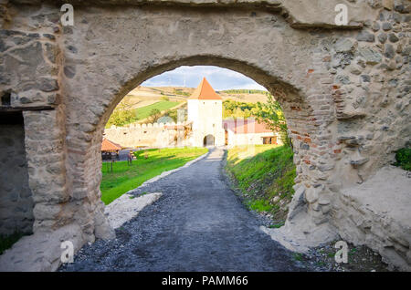 Blick durch ein altes Tor einer mittelalterlichen Festung in Rumänien mit einem Turm und Mauer auf dem Hintergrund Stockfoto