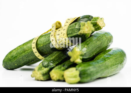 Zucchini auf einem weißen Tisch. Maßgeschneiderte messen Sie den Bauchumfang während der Diät zu messen. Hellen Hintergrund. Stockfoto