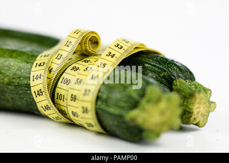 Zucchini auf einem weißen Tisch. Maßgeschneiderte messen Sie den Bauchumfang während der Diät zu messen. Hellen Hintergrund. Stockfoto