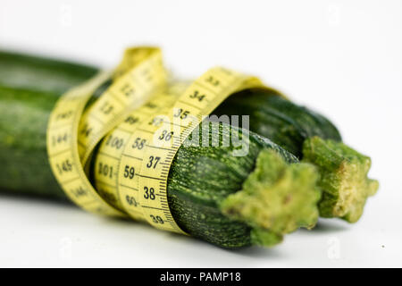 Zucchini auf einem weißen Tisch. Maßgeschneiderte messen Sie den Bauchumfang während der Diät zu messen. Hellen Hintergrund. Stockfoto