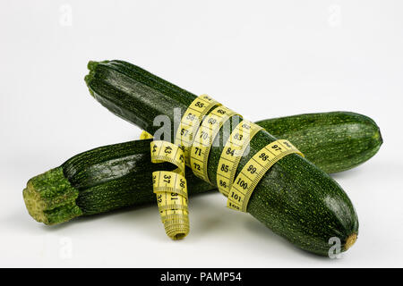 Zucchini auf einem weißen Tisch. Maßgeschneiderte messen Sie den Bauchumfang während der Diät zu messen. Hellen Hintergrund. Stockfoto