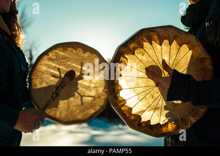 Frauen halten und spielen ihre heiligen Trommeln im Freien im Winter Stockfoto