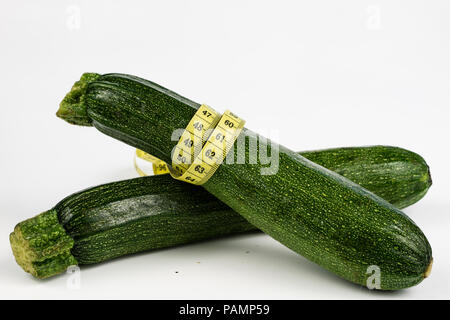 Zucchini auf einem weißen Tisch. Maßgeschneiderte messen Sie den Bauchumfang während der Diät zu messen. Hellen Hintergrund. Stockfoto