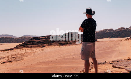 Ein Tourist aus blicken Sie über die riesigen roten Sand Landschaft des Wadi Rum Wüste in Jordanien Stockfoto